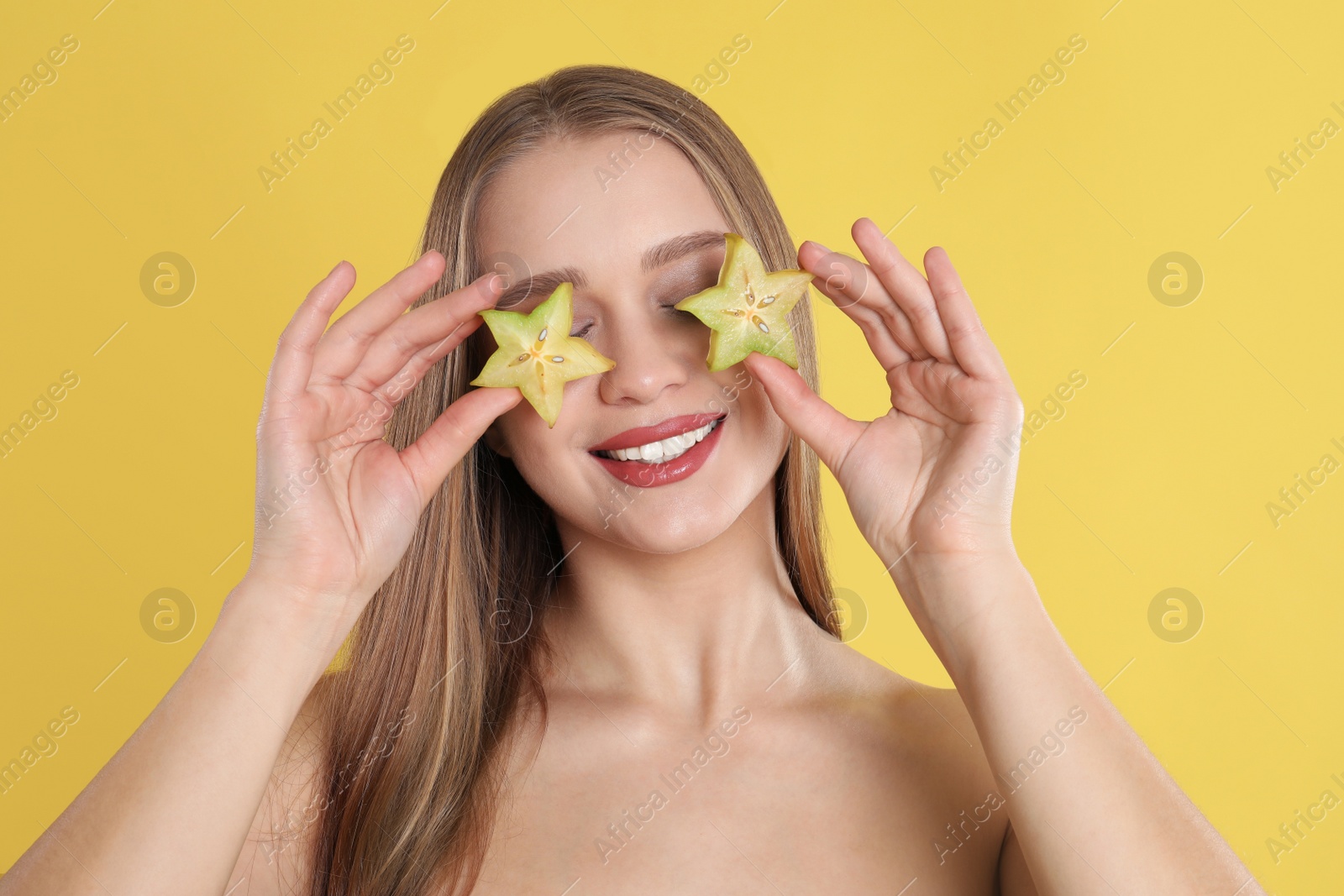 Photo of Young woman with cut carambola on yellow background. Vitamin rich food