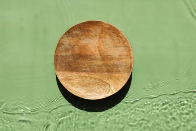 Photo of Presentation for product. Wooden podium in water on green background, top view