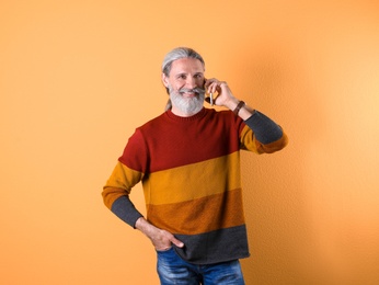 Photo of Portrait of handsome mature man with mobile phone on color background