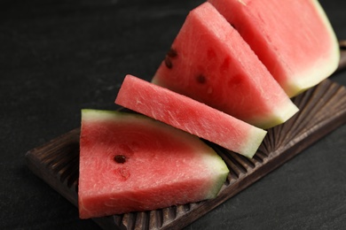 Photo of Cut ripe watermelon on black table, closeup