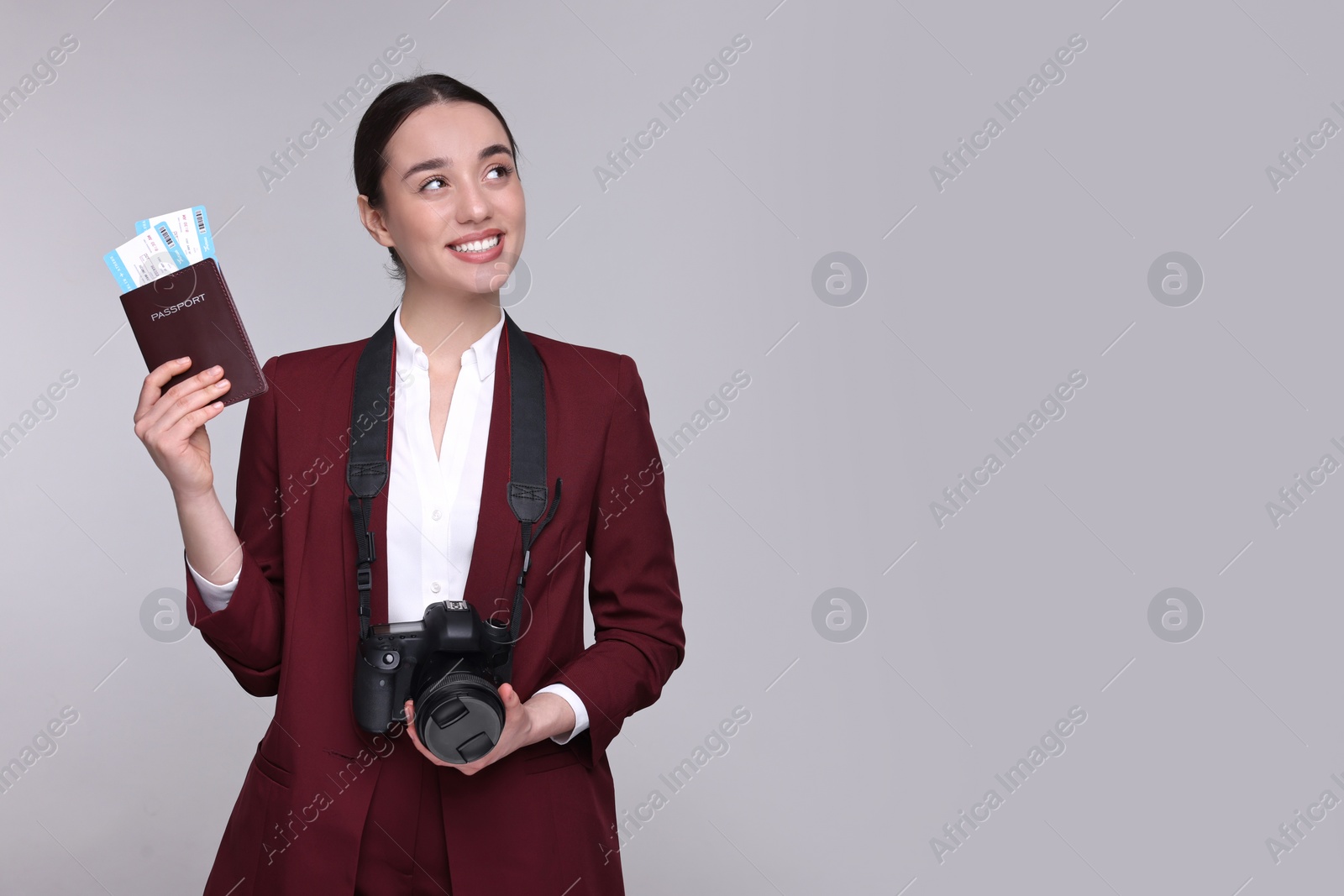 Photo of Smiling businesswoman with passport, tickets and camera on grey background. Space for text