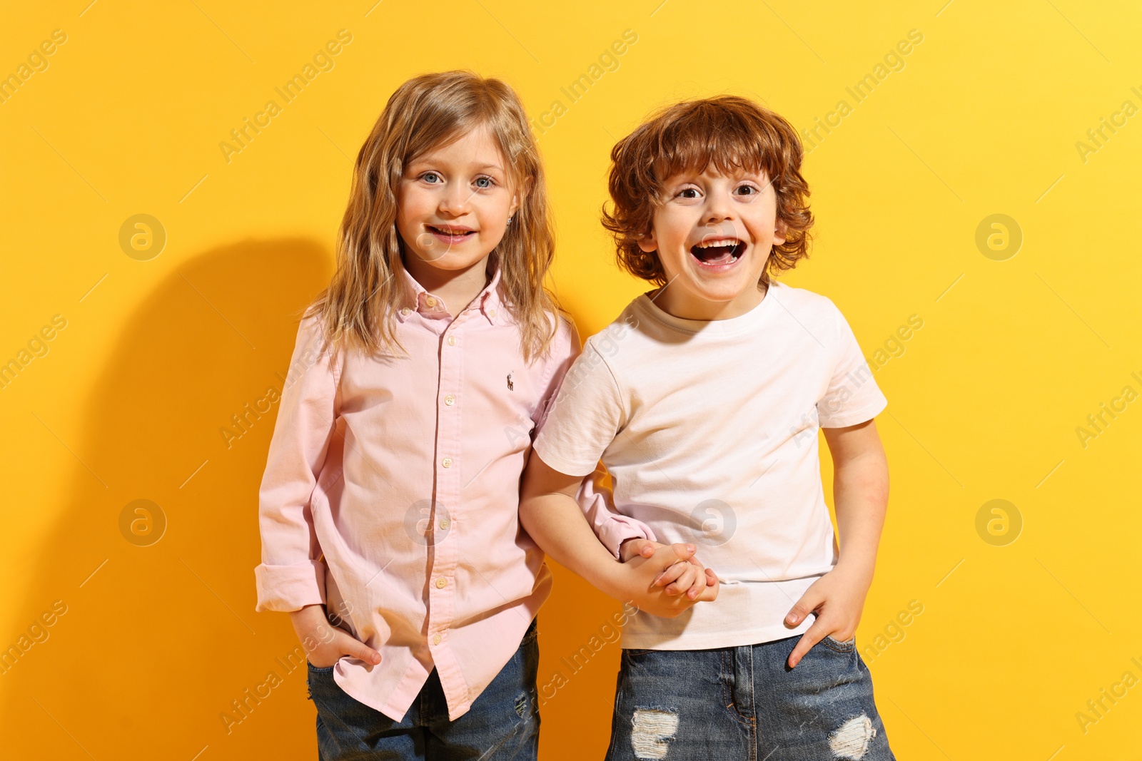 Photo of Fashion concept. Stylish children posing on yellow background