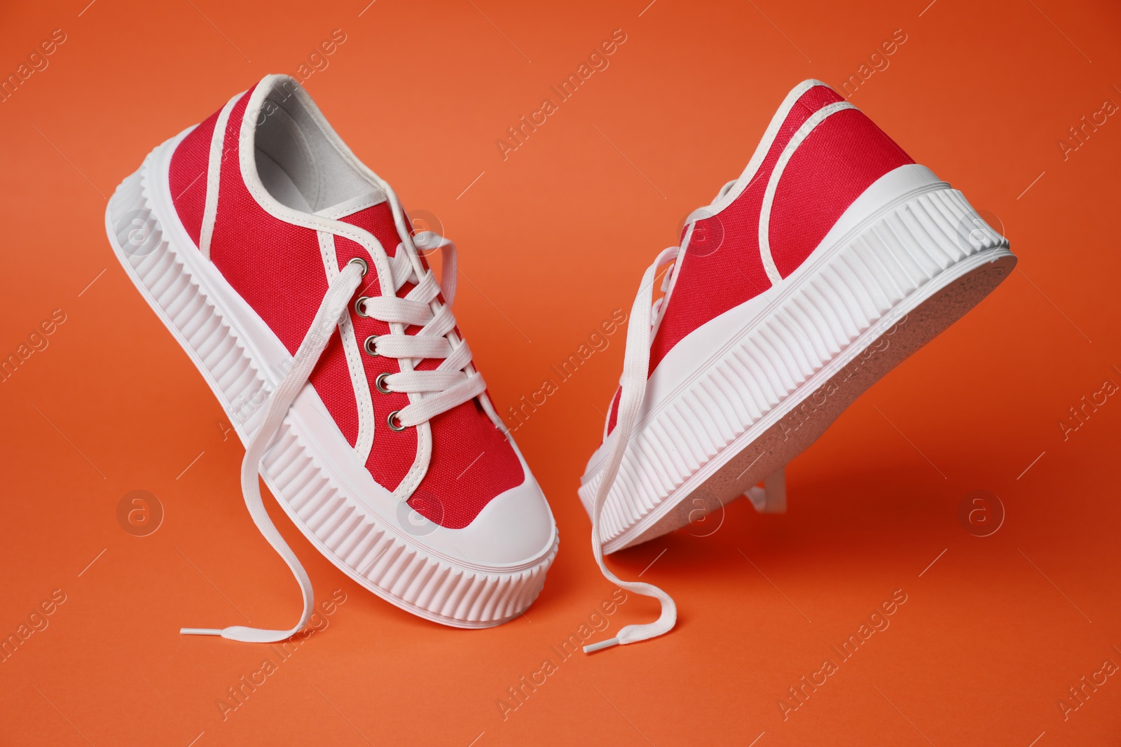 Photo of Pair of red classic old school sneakers on orange background