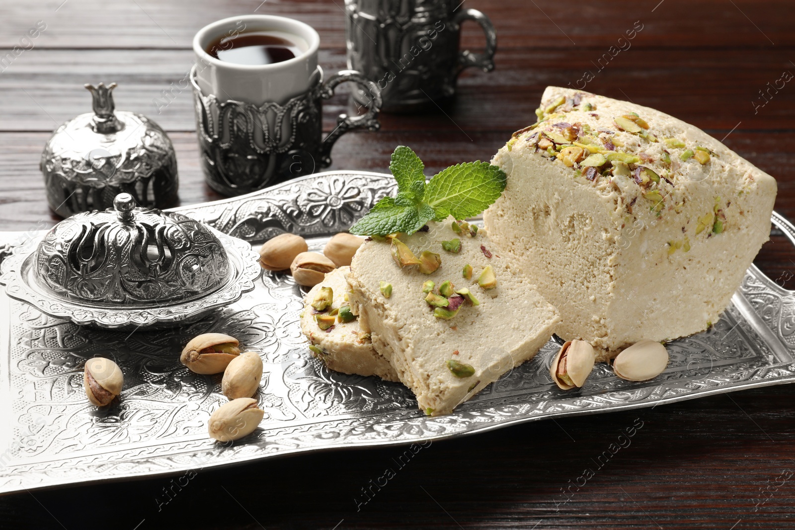 Photo of Tasty halva with pistachios and mint served on wooden table