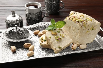 Photo of Tasty halva with pistachios and mint served on wooden table