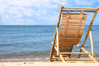 Photo of Sandy beach with empty wooden sunbed on sunny day