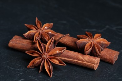 Photo of Aromatic anise stars and cinnamon sticks on black table