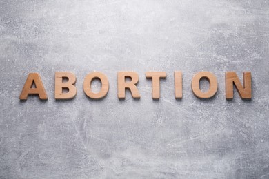 Photo of Word Abortion made of wooden letters on grey background, flat lay