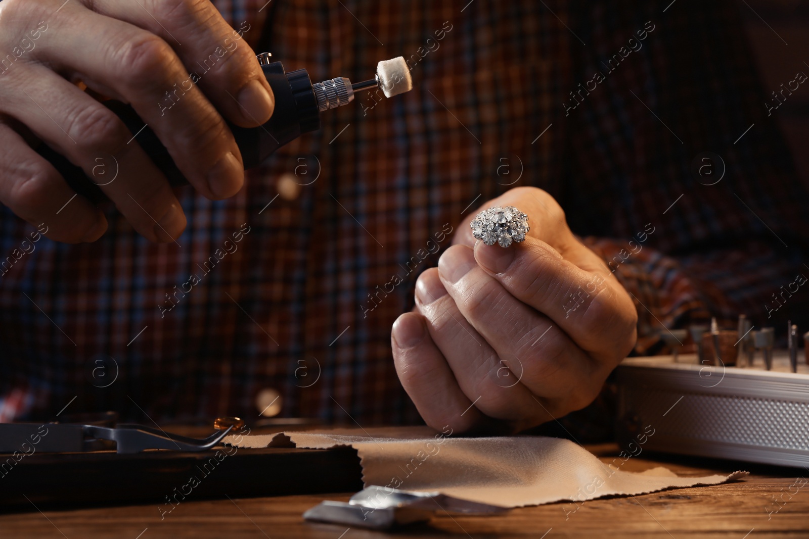 Photo of Professional jeweler working with gemstones at wooden table, closeup