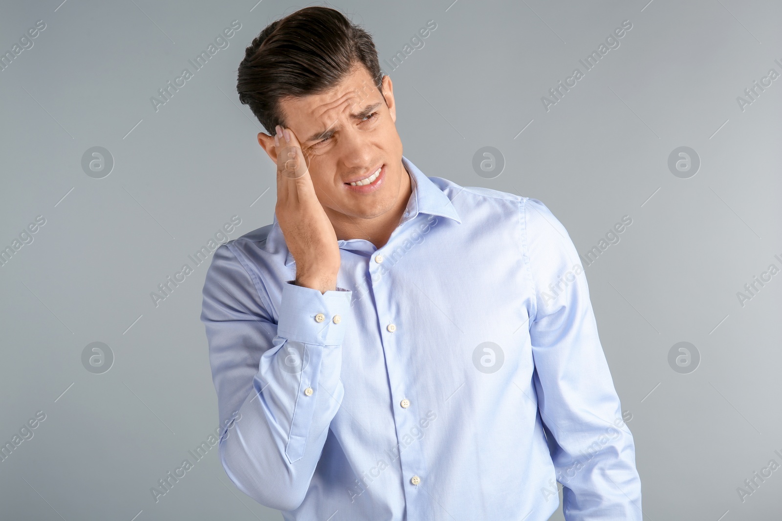 Photo of Young man suffering from headache on grey background