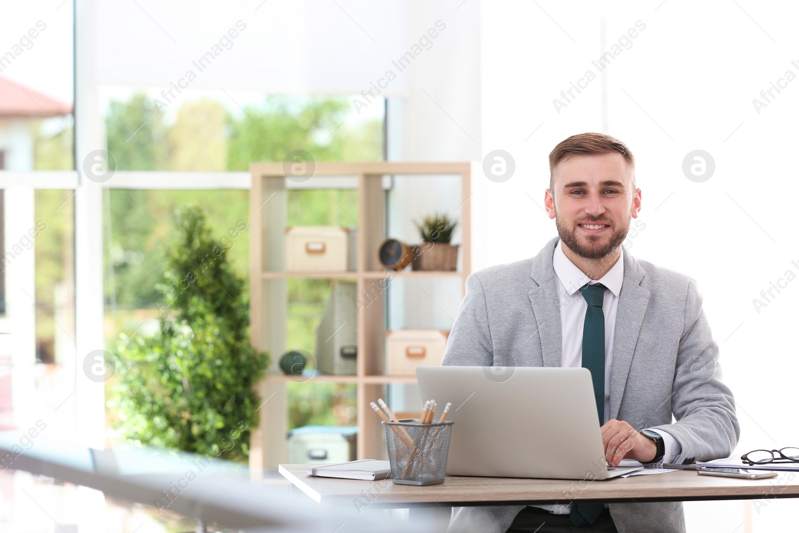 Photo of Young businessman using laptop at table in office