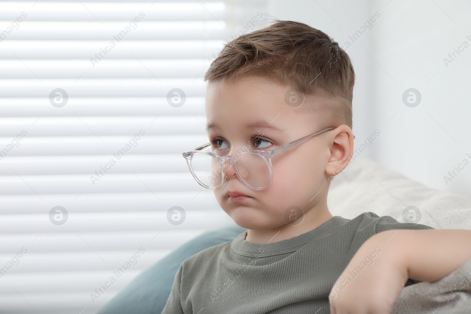 Photo of Cute little boy in glasses at home. Space for text