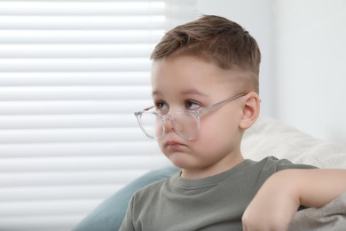 Cute little boy in glasses at home. Space for text