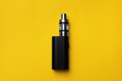 Photo of Electronic cigarette on yellow background, top view