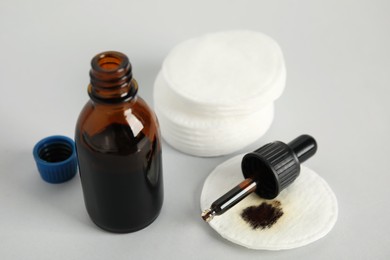 Photo of Bottle of medical iodine, dropper and cotton pads on grey background, closeup