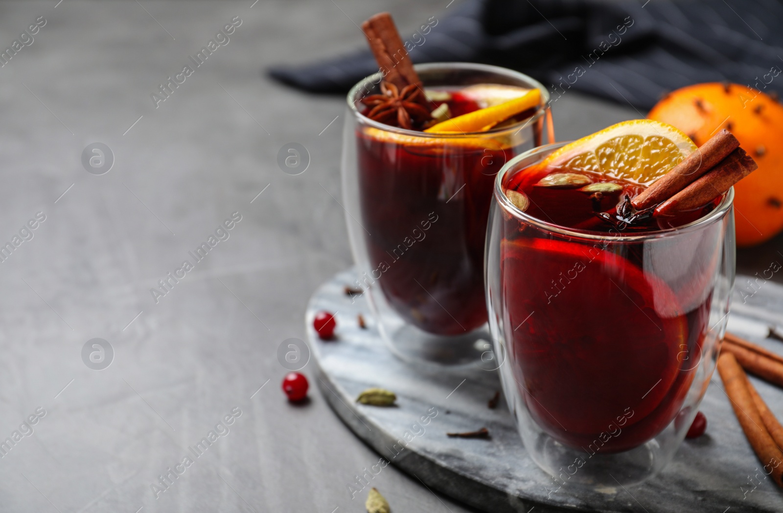 Photo of Glasses of tasty mulled wine on grey table