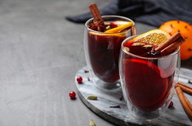 Photo of Glasses of tasty mulled wine on grey table