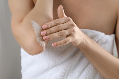 Photo of Woman applying body cream onto elbow, closeup