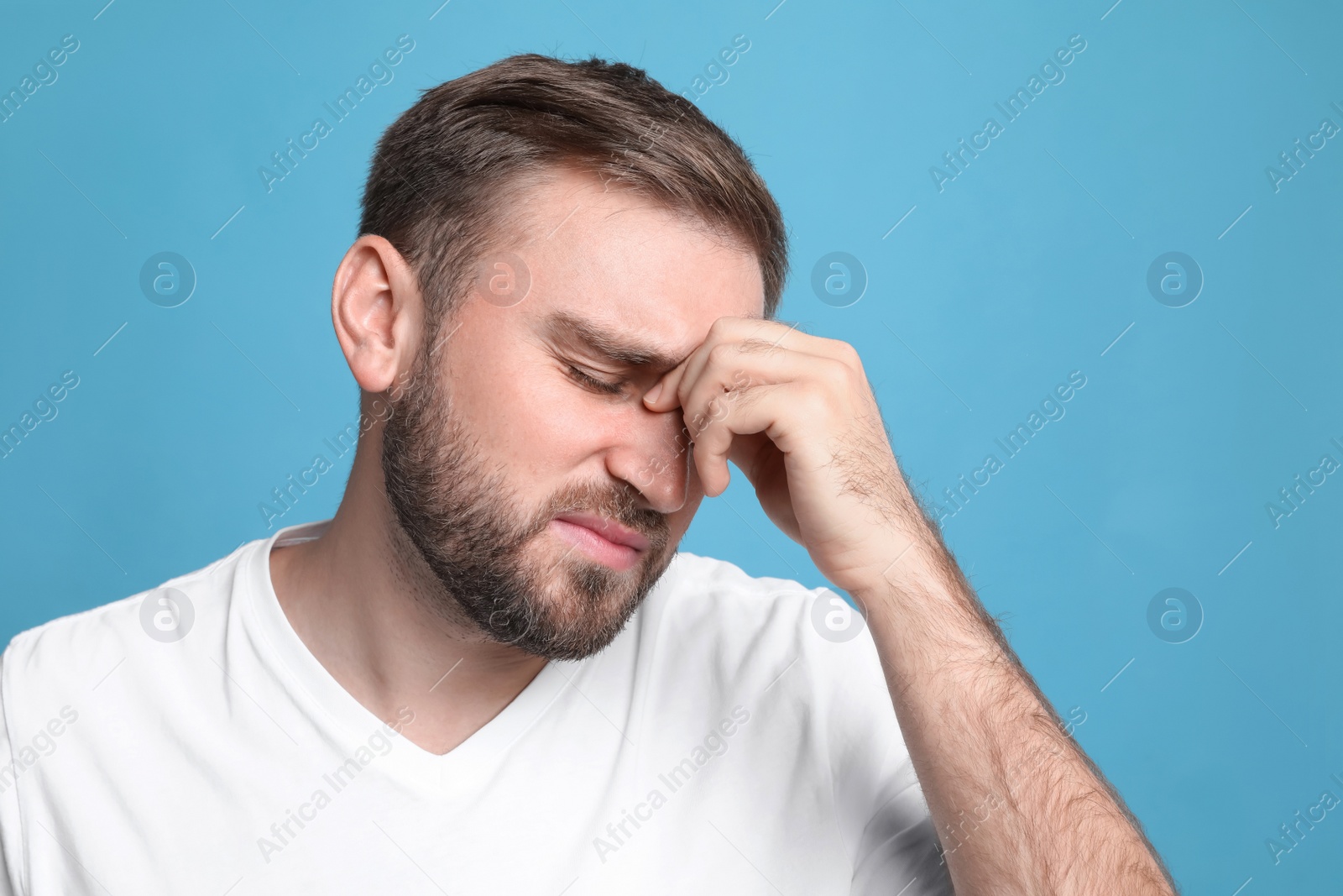 Photo of Young man suffering from headache on light blue background