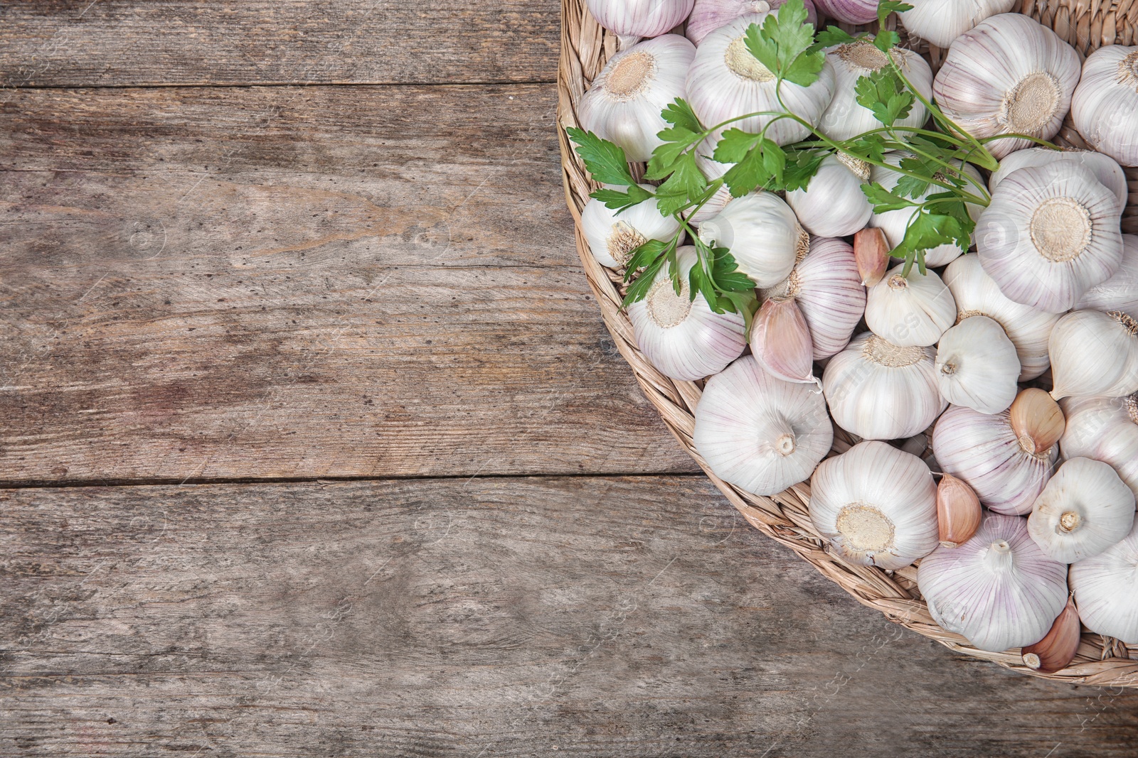 Photo of Wicker plate with fresh garlic on wooden background, top view