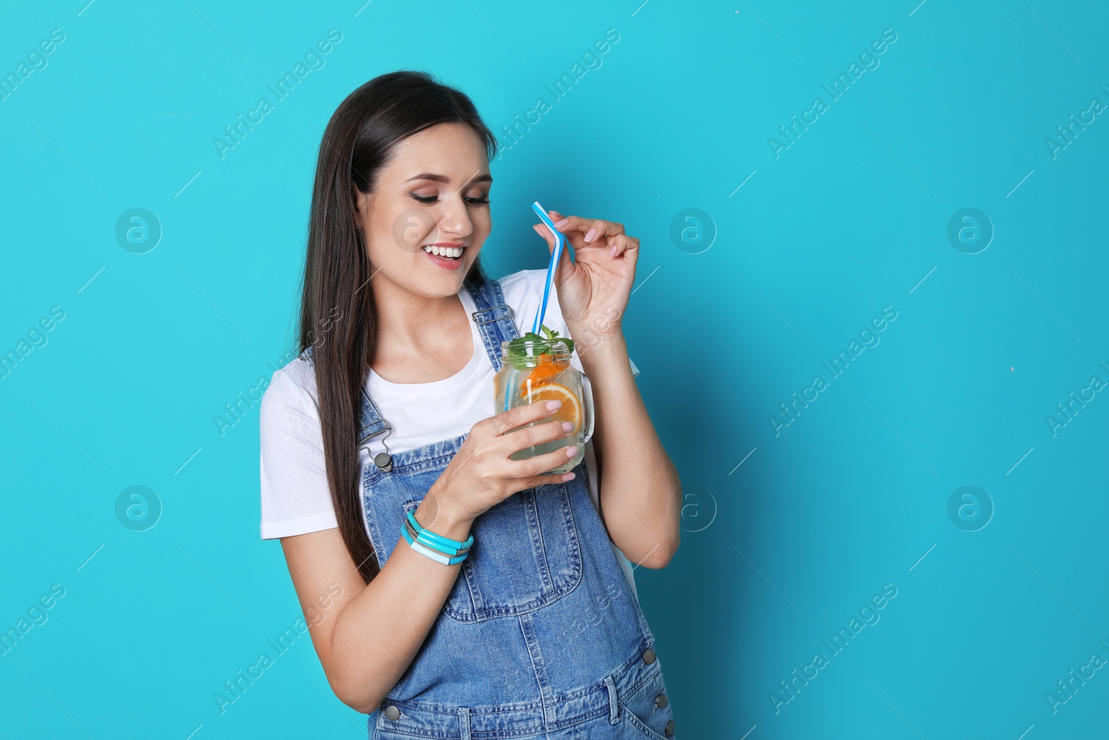 Photo of Young woman with mason jar of tasty lemonade on color background. Natural detox drink