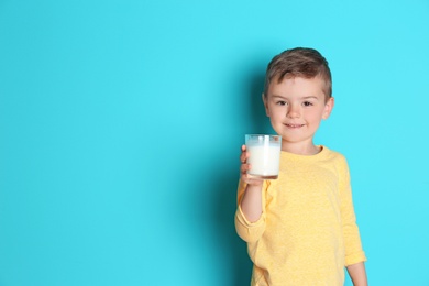 Cute little boy with glass of milk on color background