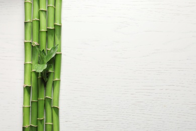 Green bamboo stems and space for text on wooden background, top view