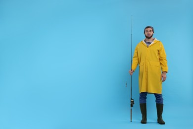 Photo of Fisherman with fishing rod on light blue background, space for text