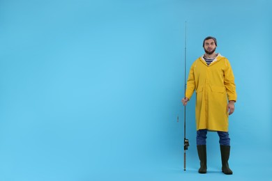 Fisherman with fishing rod on light blue background, space for text