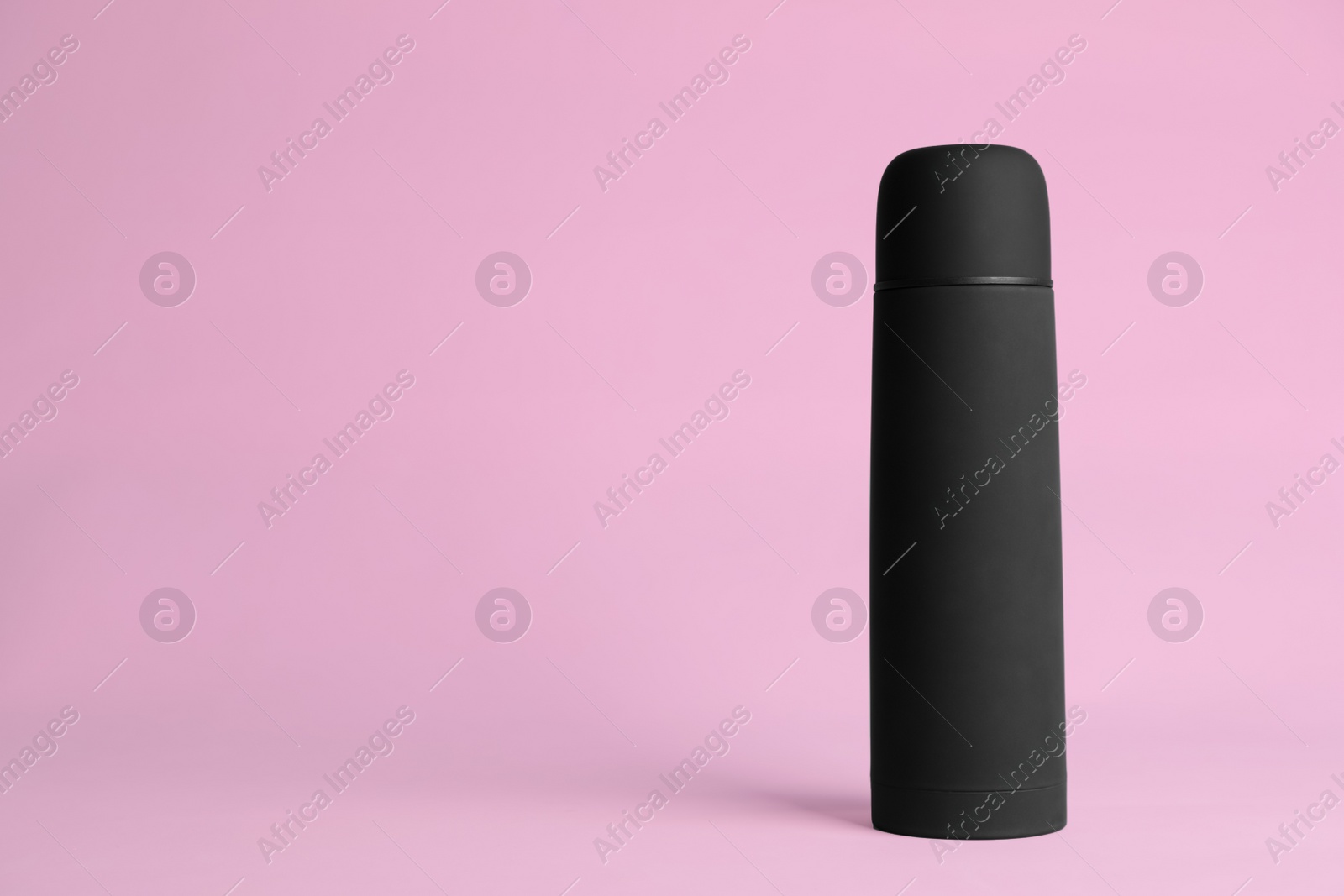 Photo of Stylish thermo bottle on pink background, space for text