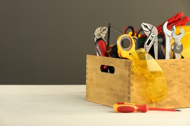 Photo of Wooden box with different tools for repair on white table, space for text