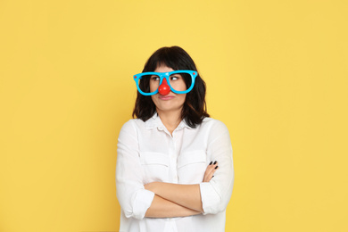 Photo of Emotional woman with funny glasses on yellow background. April fool's day