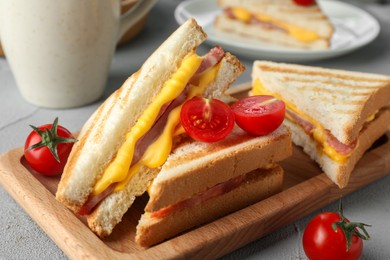 Photo of Tasty sandwiches with ham, melted cheese and tomatoes on grey textured table, closeup