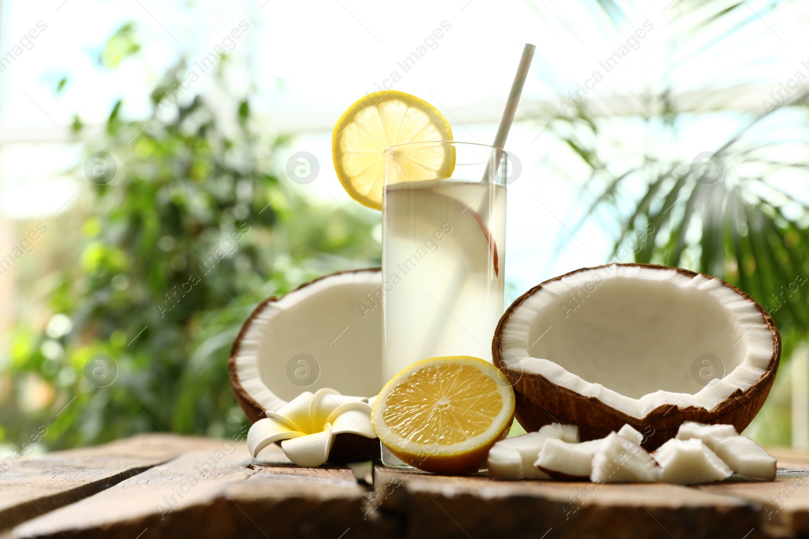 Photo of Composition with glass of coconut water and lemon on wooden table