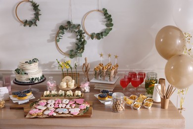 Photo of Baby shower party. Different delicious treats and drinks on wooden table indoors