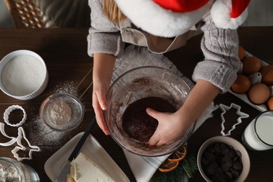 Photo of Little child making Christmas cookies at wooden table, top view