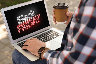 Image of Black Friday. Man shopping online using laptop outdoors, closeup