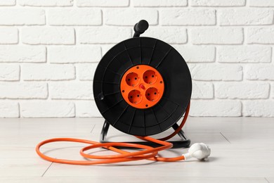 Extension cord reel on floor near white brick wall. Electrician's equipment