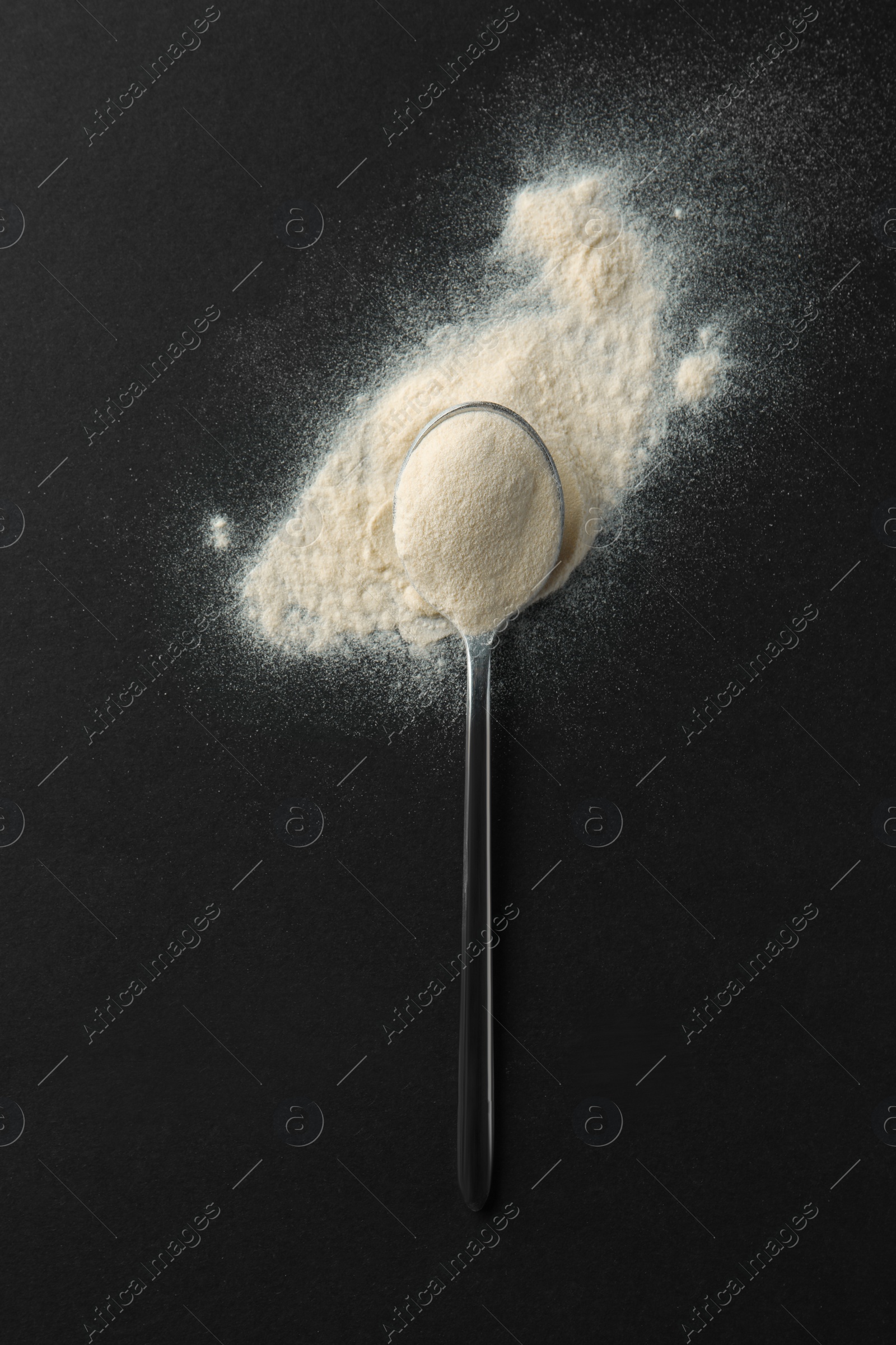 Photo of Spoon of agar-agar powder on black background, top view