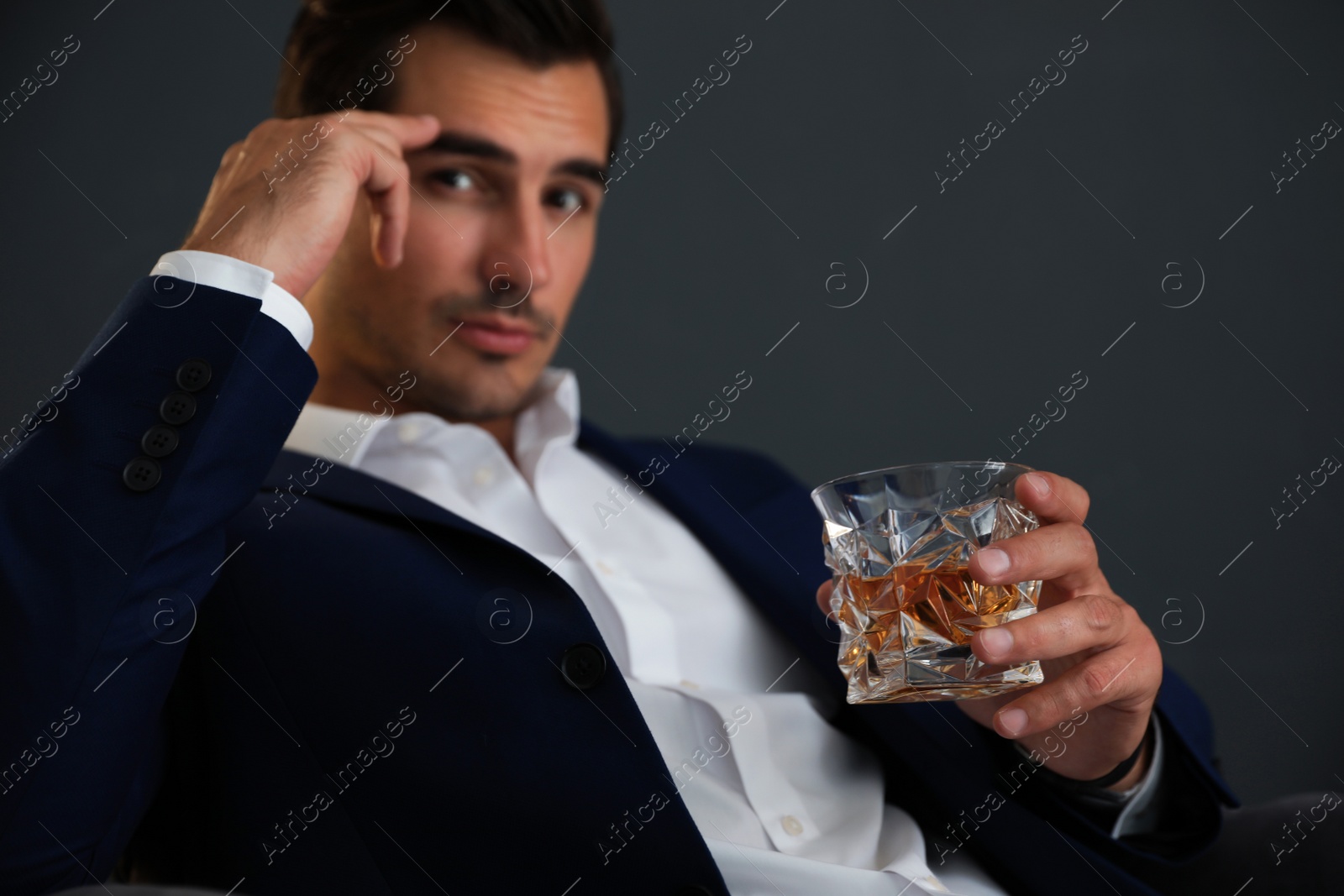 Photo of Young man with glass of whiskey on dark background