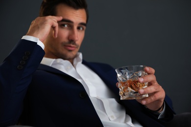 Photo of Young man with glass of whiskey on dark background