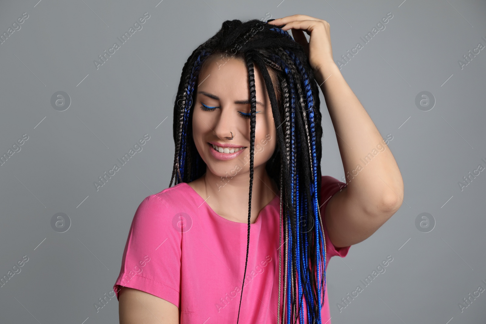 Photo of Beautiful young woman with nose piercing and dreadlocks on grey background