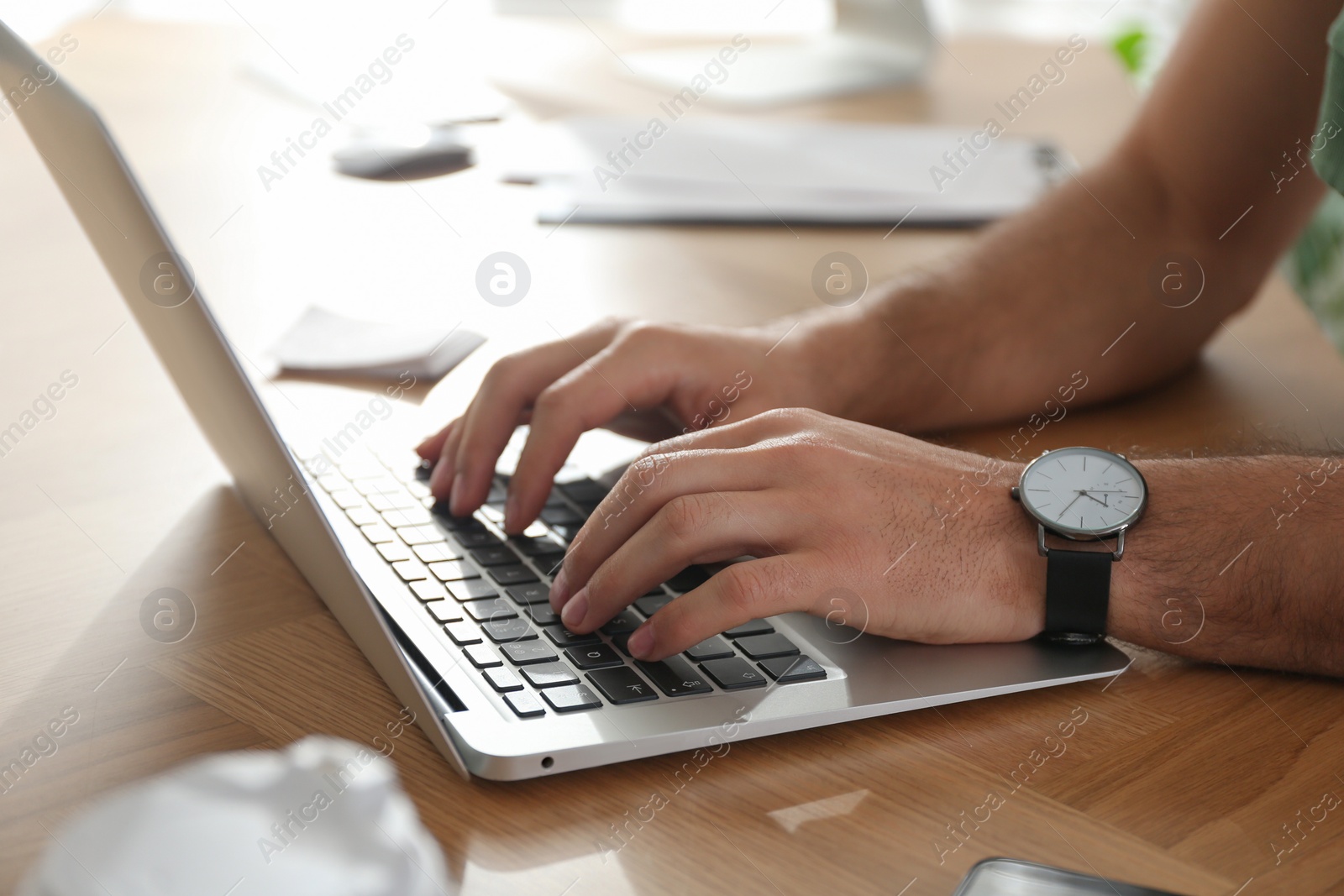 Photo of Freelancer working on laptop at table indoors, closeup