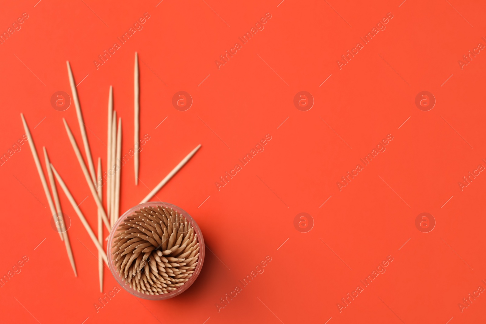 Photo of Wooden toothpicks and holder on red background, flat lay. Space for text