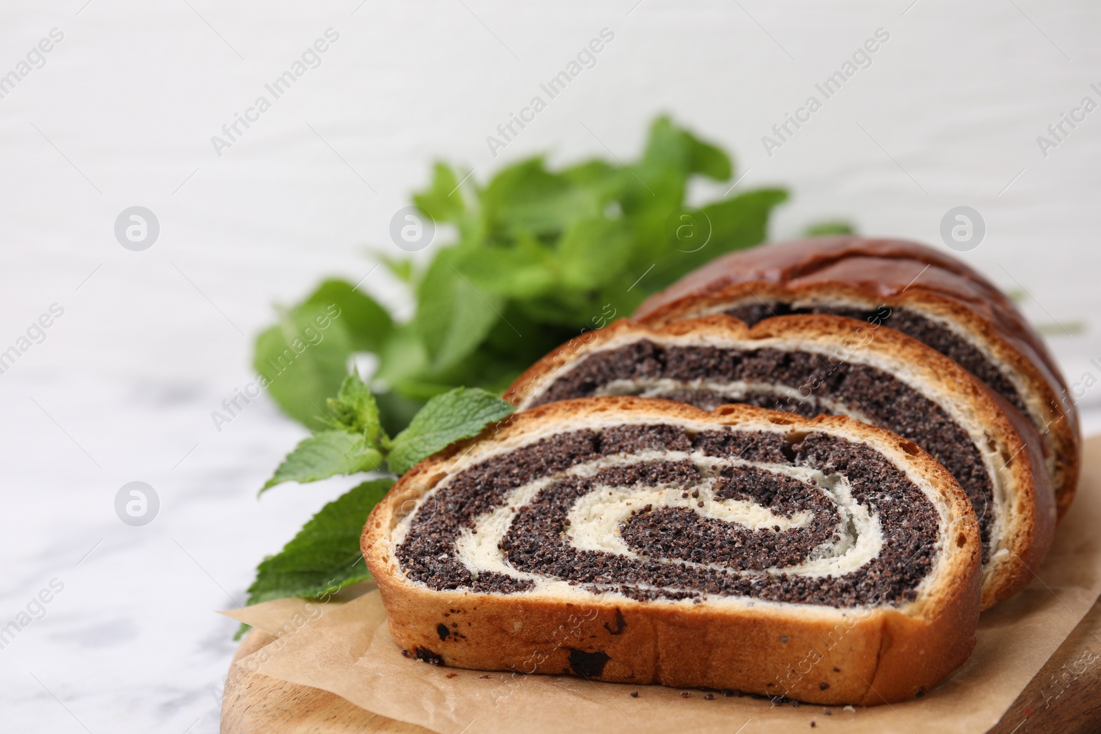 Photo of Cut poppy seed roll and mint on table, closeup with space for text. Tasty cake