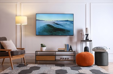 Photo of Stylish room interior with modern TV, armchair and decor