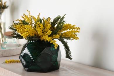Photo of Beautiful mimosa flowers on wooden table indoors, space for text