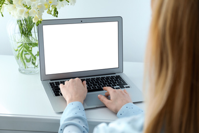 Photo of Woman working on modern laptop at white table indoors, closeup