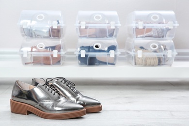 Photo of Pair of female shoes and other footwear in plastic boxes on floor. Storage organization