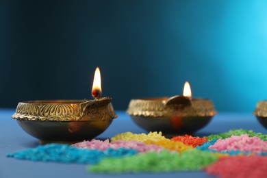 Diwali celebration. Diya lamps and colorful rangoli on blue background, closeup